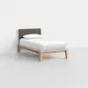 A single bed with a wooden frame and legs, a dark gray upholstered headboard, and white bedding with one pillow, set in a minimal, light gray room.