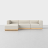 A modern, light beige sectional sofa with wooden base, featuring a left-facing chaise lounge, set against a plain white background and light gray floor.