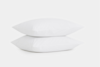 Two clean, white pillows stacked on top of each other against a plain white background.