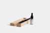 A small wooden box with a row of black spherical objects inside, next to a small dropper bottle labeled DEEP FOREST on a plain white background.