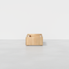 A minimalist wooden storage box with open compartments is placed on a smooth, light gray surface against a plain white background.