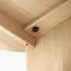 Close-up view of the underside of a light wood table, focusing on the corner joint where two pieces meet and are secured by a visible black screw. The wood grain and smooth finish are clearly visible.
