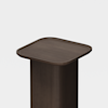 A minimalist, dark wooden pedestal table with a square, gently rounded top and smooth edges, set against a plain white background.