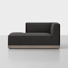 A modern dark gray upholstered chaise lounge with a right-side backrest and armrest, set on a light wooden base, placed in a minimalist room with a light floor and white background.