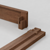 Two pieces of wooden furniture with interlocking joinery are positioned on a light gray surface, showing the precise craftsmanship and fit of the connecting parts.