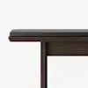 Close-up side view of a dark wooden bench with a black cushioned seat against a plain white background.