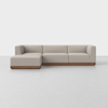 A modern beige sectional sofa with clean lines and a low wooden base, set on a smooth, light gray floor against a plain white background.