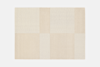 A rectangular area rug featuring a grid pattern of alternating beige and cream-colored squares.