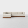 A modern, L-shaped sectional sofa with light beige upholstery and a wooden base, set against a plain white background on a light gray floor.