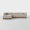 A modern, L-shaped sectional sofa with light beige upholstery and a low wooden base, set against a plain white background.