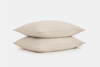 Two beige pillows are stacked on top of each other against a plain white background.