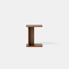 A small, modern wooden side table with an I-shaped structure, featuring a flat top and base, set against a plain white background.