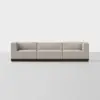 A modern, three-seat modular sofa with light beige upholstery and a dark wooden base, set against a plain white background.