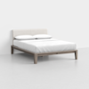 A minimalist bed with a light wood frame and an upholstered cream-colored headboard, dressed in white bedding and two pillows, set in a plain, light-colored room.