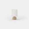A cylindrical table lamp with a beige base and a light-colored fabric shade.