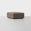 A square, brown upholstered ottoman with a simple, modern design sits on a light gray floor against a plain white background.