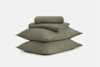 A set of neatly folded olive-green bed sheets stacked on top of two matching pillows, all placed against a plain white background.