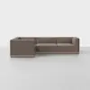 A modern, L-shaped sectional sofa with brown upholstery and low, boxy arms sits on a light gray floor against a plain white background.