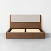 A modern wooden bed frame with an upholstered beige headboard, shown without a mattress, on a light gray floor against a plain white wall.