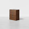 A modern, four-drawer wooden dresser with a smooth, dark brown finish, standing alone on a light gray floor against a plain white background.
