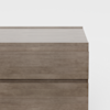 A close-up view of the top part of a light brown wooden dresser with a modern, minimalist design, set against a plain white background.