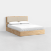A wooden platform bed with a beige upholstered headboard, white sheets, and two white pillows, set against a plain white background.