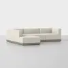 A modern, L-shaped sectional sofa with cream-colored upholstery and a low wooden base, set against a plain white background.