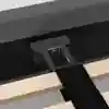 Close-up view of a bed frame showing a dark fabric headboard, a black metal support bracket attached to it, and light wooden slats with a black fabric strap across them.