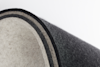 A close-up of a rolled-up piece of thick, multi-layered felt fabric showing layers in shades of black, gray, and off-white against a plain white background.