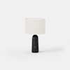 A modern table lamp with a cylindrical black marble base and a round, white fabric lampshade, set against a plain white background.