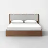 A modern wooden bed with a light gray upholstered headboard, white bedding, and two white pillows, placed against a plain white wall on a light gray floor.