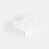 A neatly stacked set of white towels of varying sizes on a plain white background.