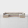 A large, modern, U-shaped sectional sofa with light beige cushions and a wooden base, set against a plain white wall and floor.