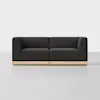 A modern black sofa with square armrests and cushions sits on a light wood base in a minimalist, white room.