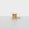 A small, modern wooden coffee table with a square top and base, featuring a central support with a minimalist design, set against a plain white background.