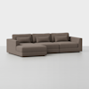 A modern, L-shaped sectional sofa upholstered in taupe fabric, featuring clean lines and three seat cushions with matching back and lumbar pillows, set against a plain white background.