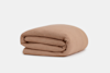 A neatly folded, light brown textured blanket is displayed on a plain white background.