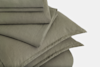 A neatly folded stack of olive green bed linens, including pillowcases and sheets, displayed against a plain white background.