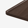 A close-up of the corner of a rectangular wooden tray with rounded edges and a shallow lip, shown on a white background.