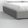 A close-up of a modern bed with a gray upholstered frame and white bedding, positioned on a smooth, light gray floor.