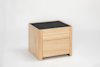 A modern wooden nightstand with light wood finish, featuring two drawers and a dark, textured top surface, set against a plain white background.