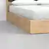 Close-up of the corner of a light wood bed frame with white bedding and pillows, set on a smooth, light gray floor.