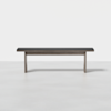 A modern bench with a black cushioned seat and light wood legs, placed on a smooth, light-colored floor against a plain white background.
