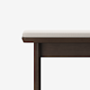 A close-up of a wooden bench with a dark brown frame and a light beige cushioned seat, shown against a plain white background. Only one corner and one leg of the bench are visible.