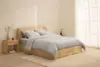 Two white pillows stacked on top of a neatly folded white comforter against a plain white background.