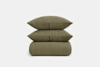 Three olive green, textured cushions are neatly stacked on top of each other against a plain white background.