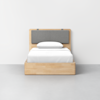 A minimalist wooden bed with a light wood frame, gray cushioned headboard, and white bedding, set against a plain white wall and gray floor.