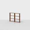 A simple, modern wooden bookshelf with three shelves and four vertical supports stands on a light gray floor against a plain white background.