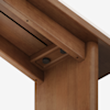 Close-up view of a wooden table or desk corner, showing the joint and fasteners underneath the tabletop, highlighting smooth wood grain and precise construction details.