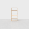 A simple, light wood bookshelf with five open shelves stands empty on a light grey floor against a plain white background.